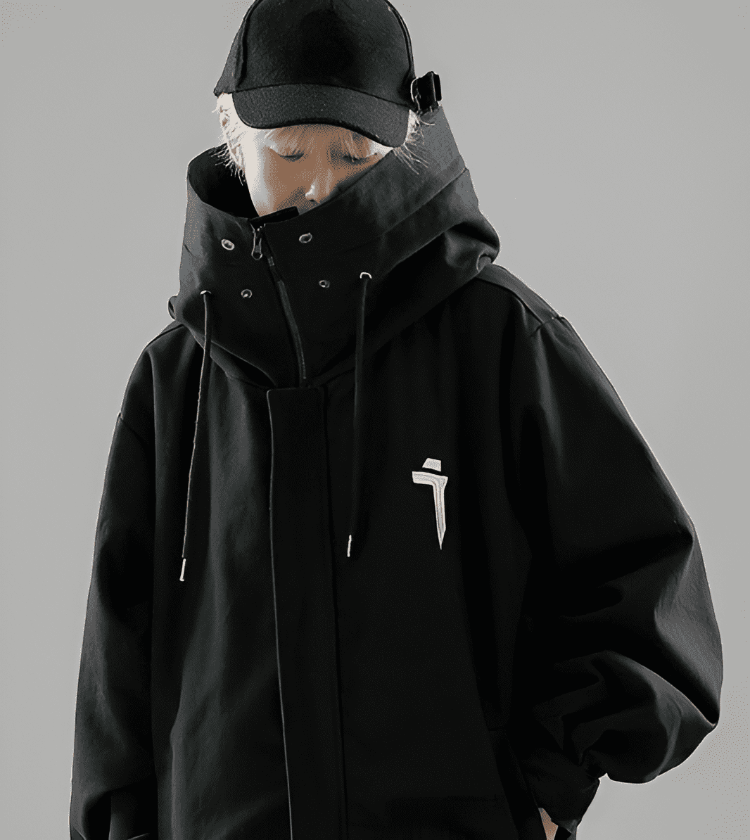 Veste ERI techwear noir porter par un homme de face avec une casquette noire