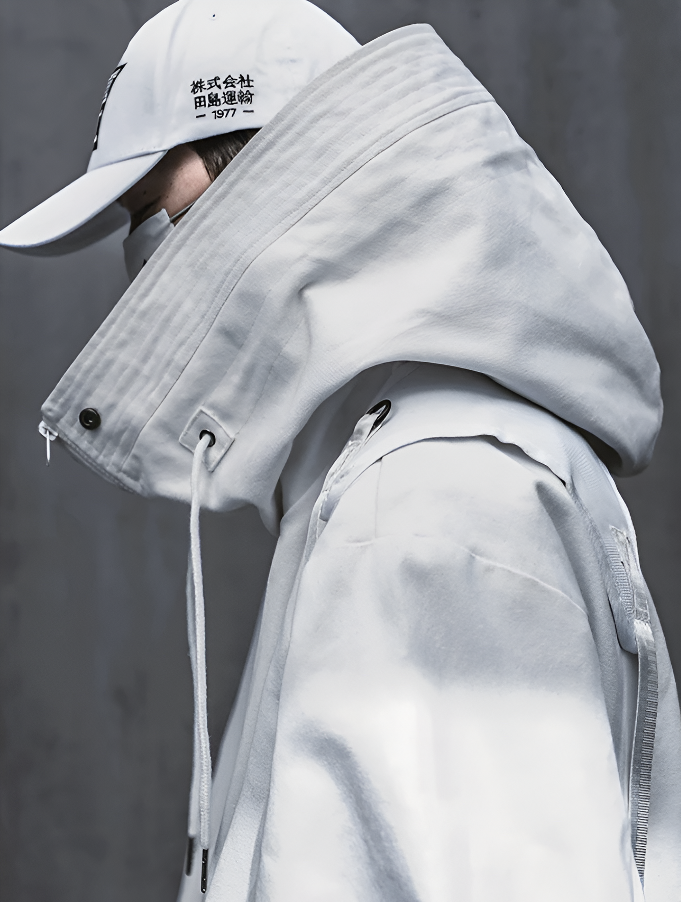 Veste ERI techwear blanche porté par un homme de profil avec une casquette